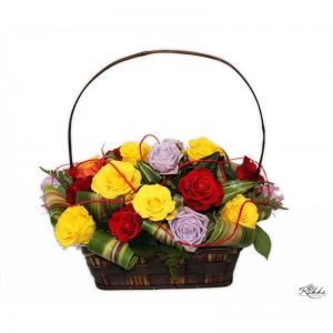 Koszyk z kolorowych róż z dodatkiem wywiniętych liści kordyliny.